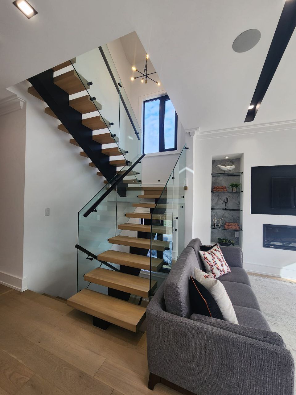 Custom architectural staircase with solid wood treads and glass railings in North York home